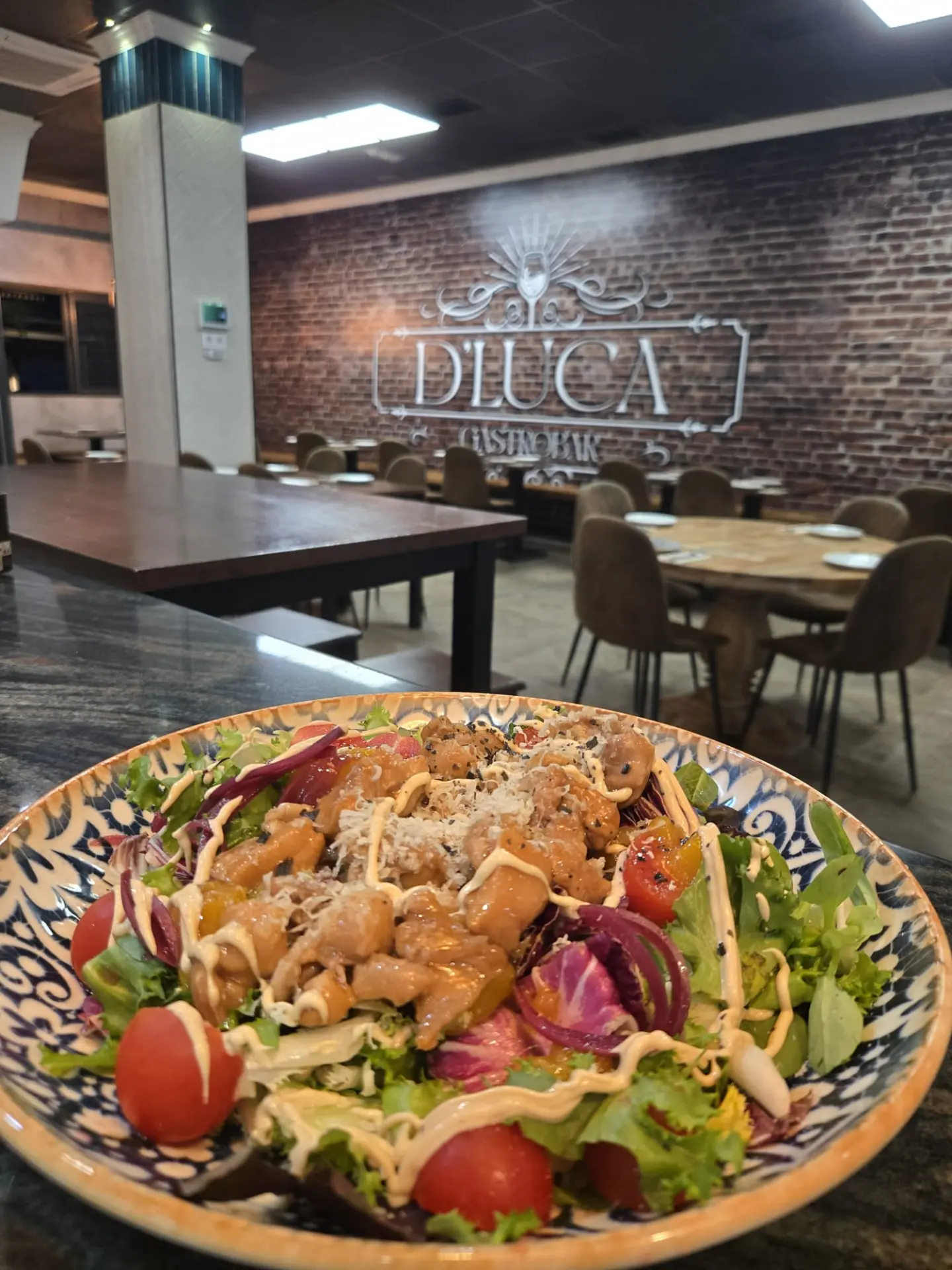 Ensalada de pollo crujiente con tomate y queso rallado en la sala de D'Luca Gastrobar