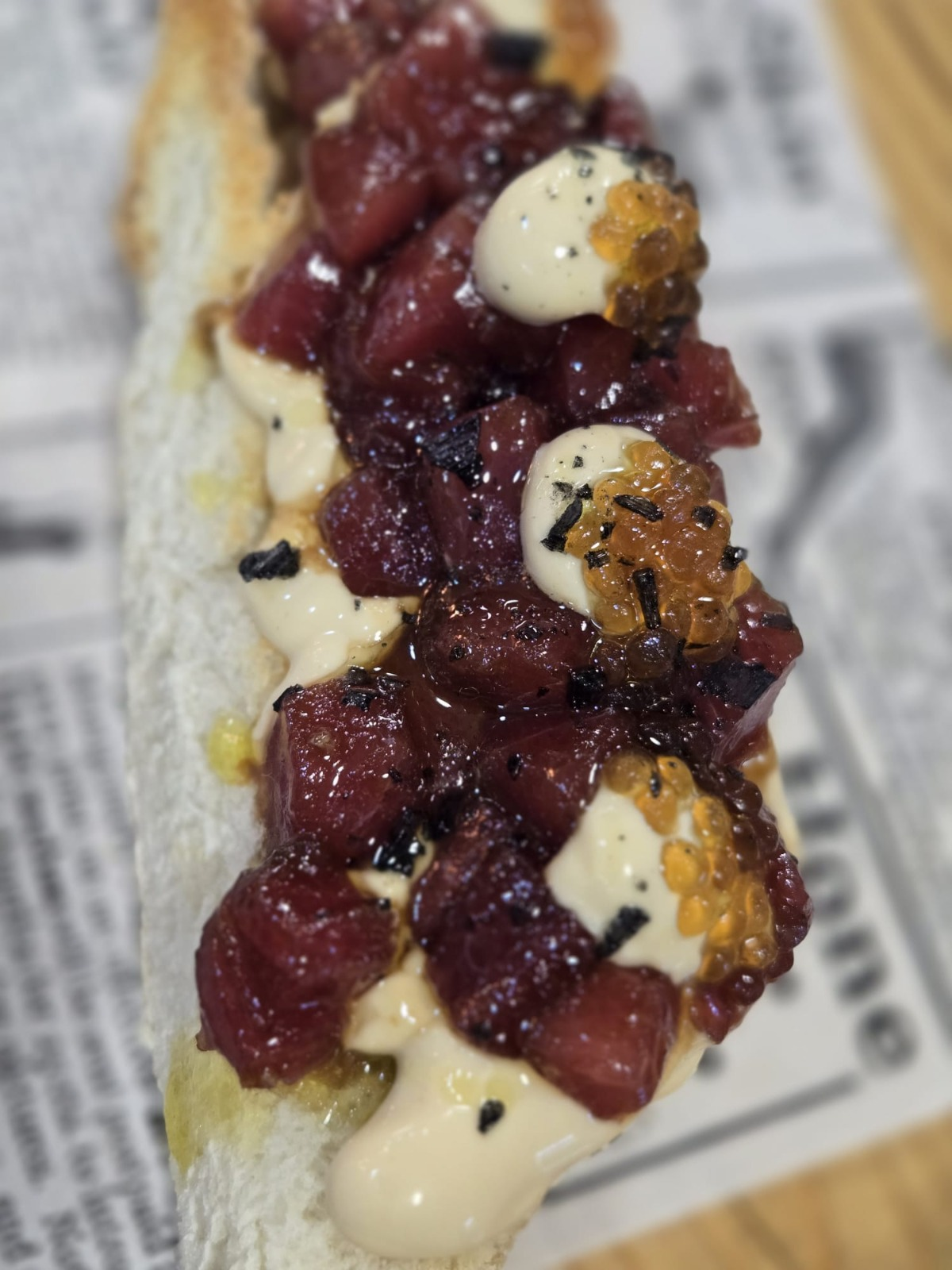 Tosta de tartar de atún con huevas y crema, servida sobre papel