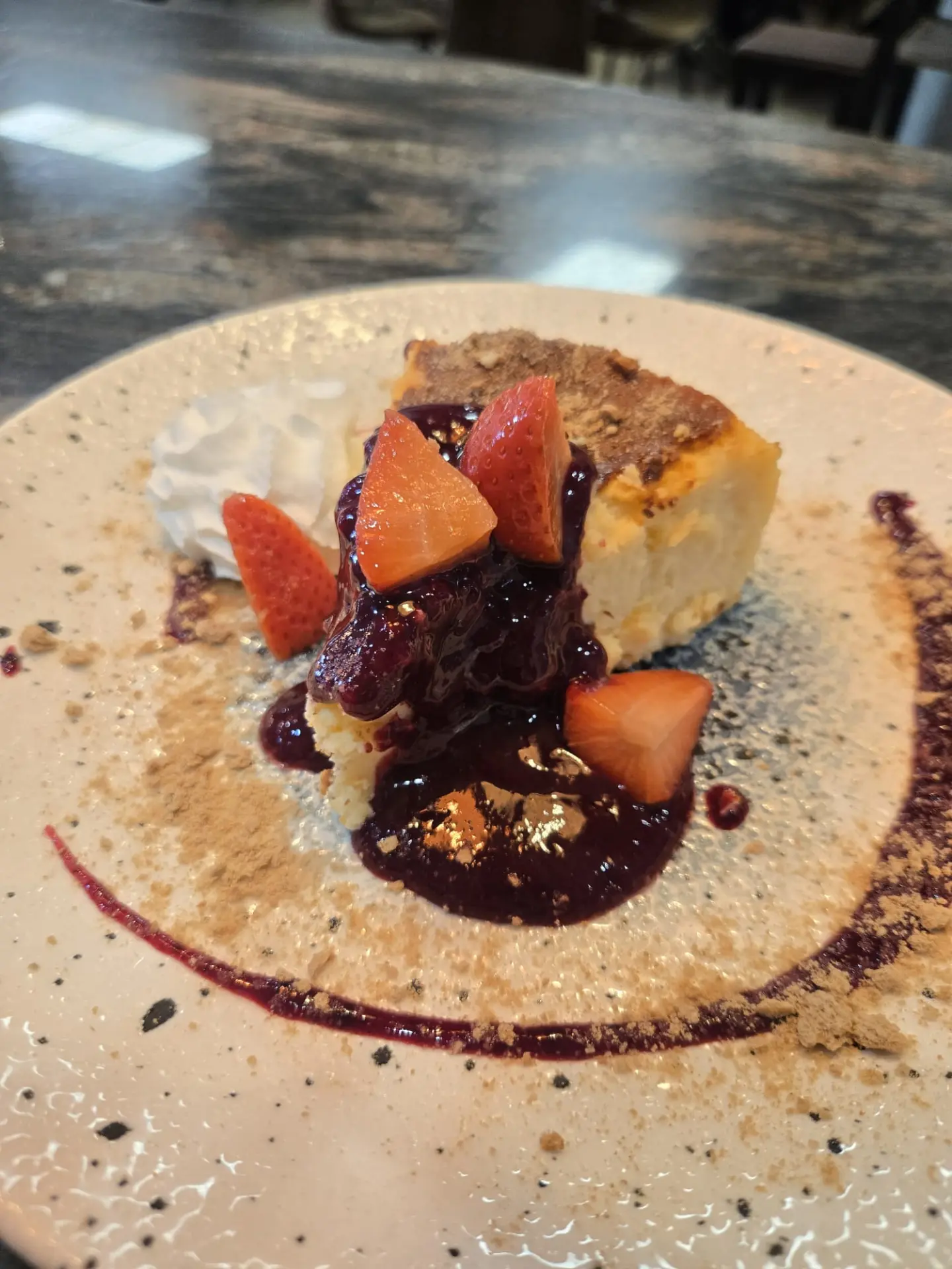 Porción de tarta de queso con nata y coulis de frutos rojos