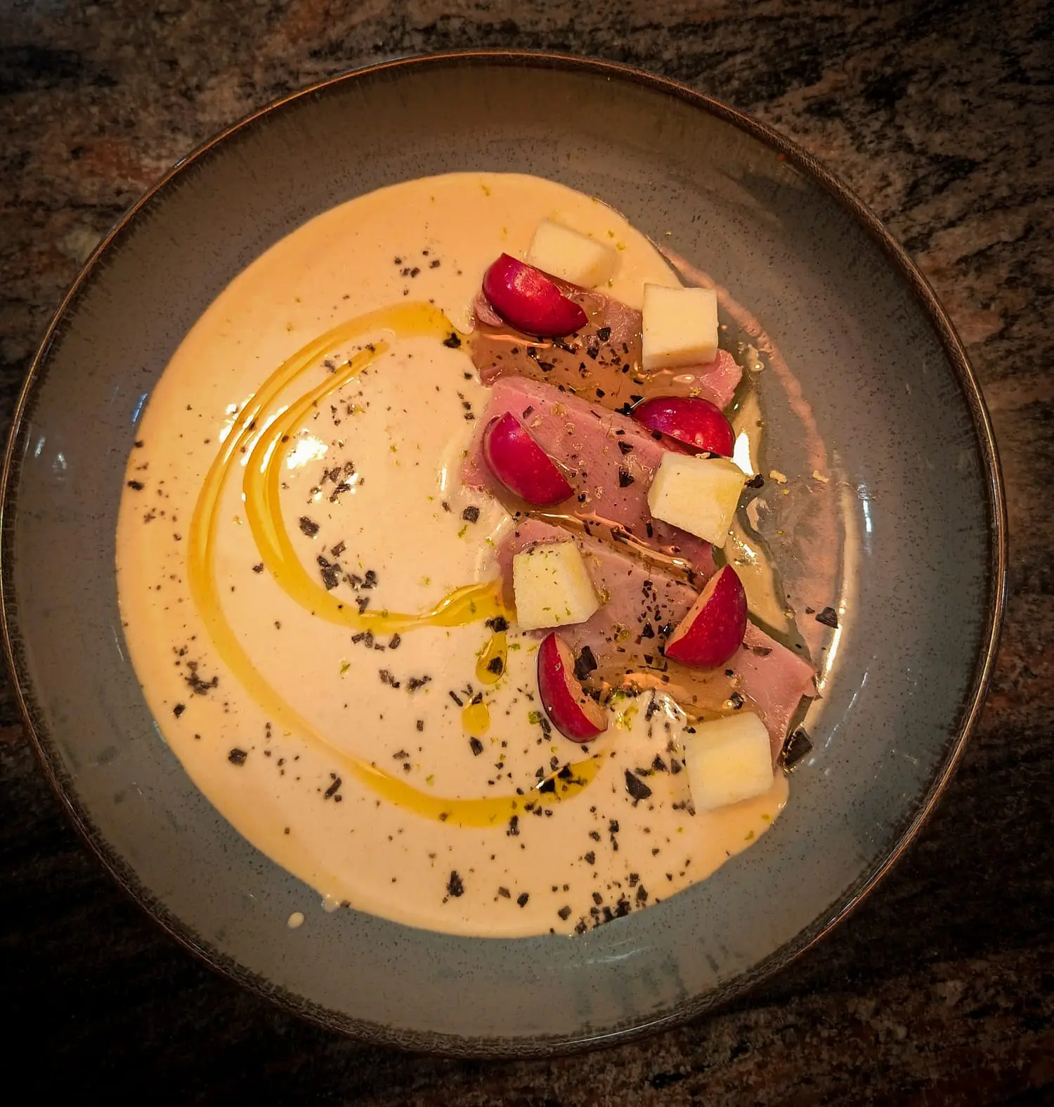 Lomo curado con crema, manzana y uvas sobre plato de gres